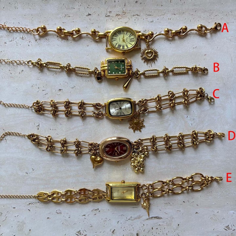 Pode incluir: Cinco pulseiras de rel&oacute;gio vintage douradas com diferentes mostradores e designs de corrente. Cada rel&oacute;gio tem um formato de mostrador &uacute;nico e &eacute; adornado com berloques, incluindo cora&ccedil;&otilde;es, s&oacute;is e uvas. Os rel&oacute;gios est&atilde;o rotulados de A a E.
