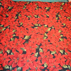 Könnte beinhalten: Roter Weihnachtsstern mit goldenen Akzenten auf schwarzem Hintergrund. Der Stoff hat ein sich wiederholendes Muster aus den Blumen.