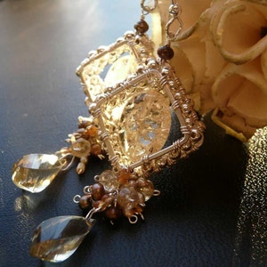 May include: Silver wire earrings with a clear crystal cage and brown and clear gemstone accents.