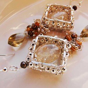 May include: A pair of silver wire wrapped earrings with clear quartz stones and brown and gold beads.