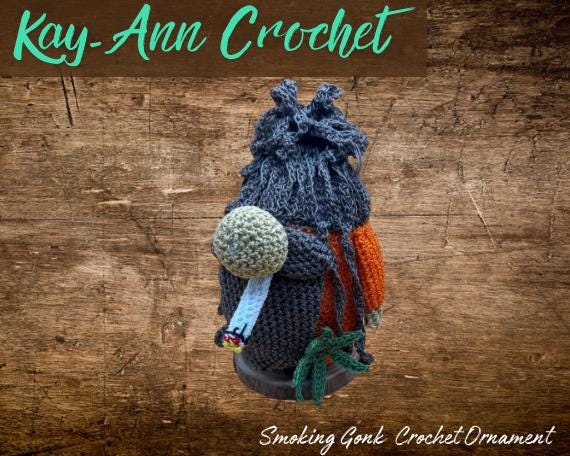 A tiny crocheted gnome (gonk) cheekily holding a cigarette — the 'smoking gonk' is a genuinely funny subversion of the cute holiday character trend.