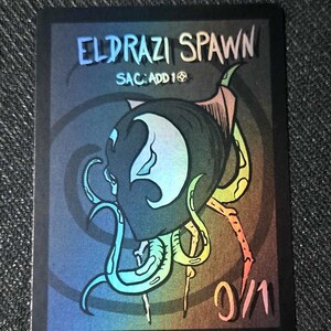 May include: A rectangular game card featuring a dark, gradient background with a central illustration of a multi-tentacled creature. The text reads ELDRAZI SPAWN, SAC: ADD 1, and 0/1. The card has a black border and a holographic, rainbow-colored finish.