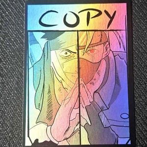Op de afbeelding: Een rechthoekige holografische verzamelkaart met het woord COPY in zwarte letters bovenaan. De afbeelding toont een illustratie van een gezicht in twee delen van een personage met een hoofdband en masker, met de handen tegen elkaar.