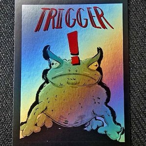 May include: A rectangular trading card with a black border featuring a holographic background. The card displays a green toad illustration with a red exclamation point above its head and the word TRIGGER printed in red capital letters above.