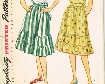 May include: A vintage Simplicity sewing pattern envelope, number 1916, size 12, bust 30. The illustration shows two dress variations: one with a white ruffled top and green striped skirt, and one with a yellow floral print off-the-shoulder dress.