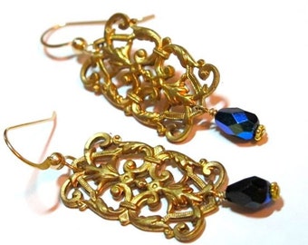 Könnte beinhalten: Goldene Filigranohrringe mit blauen und schwarzen Glas-Tropfenanhängern.