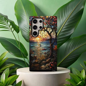 Peut inclure: Une coque de téléphone avec un motif de vitrail coloré représentant un arbre avec un coucher de soleil en arrière-plan. La coque a une découpe pour l'objectif de l'appareil photo.