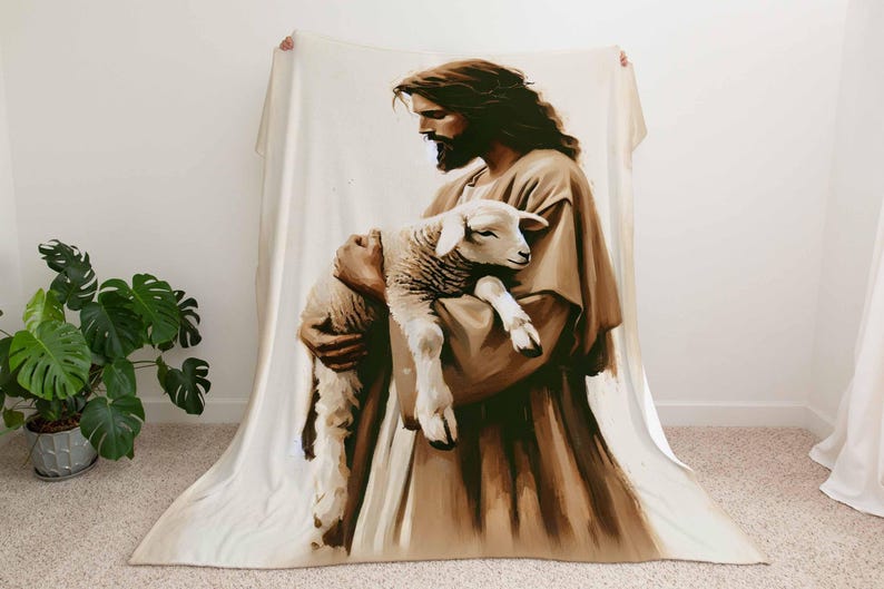 Op de afbeelding: Een bruin en wit fleece deken met een schilderij van een man die een lam vasthoudt. De man draagt een lange robe en heeft een baard. Het lam is wit en heeft een zwarte neus.