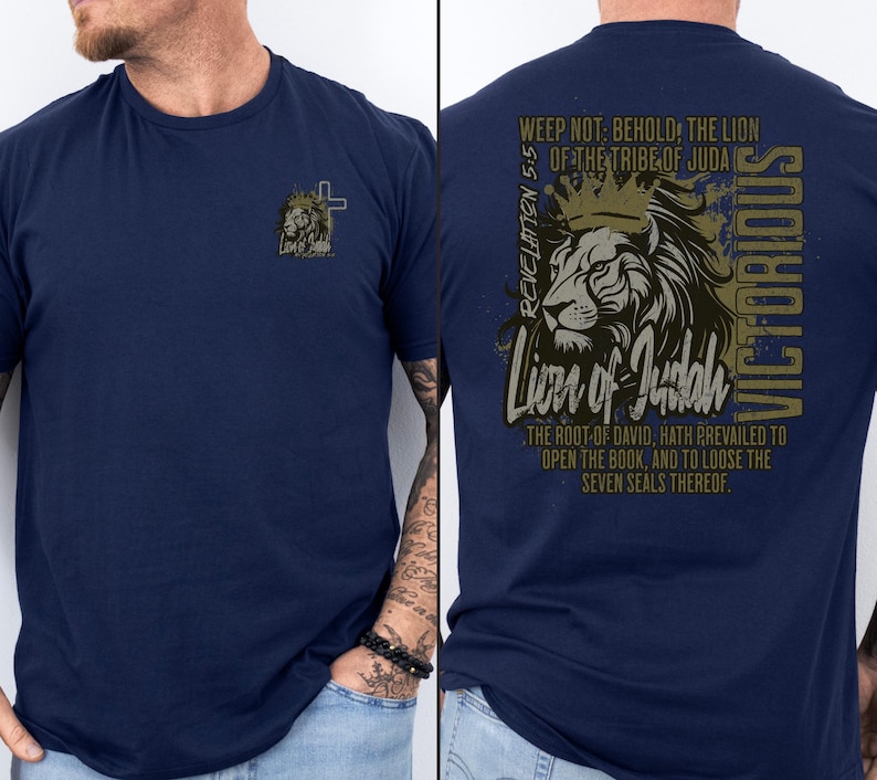 May include: A navy blue t-shirt with a lion graphic on the back. The graphic features a lion with a crown, the text "Lion of Judah", and the Bible verse Revelation 5:5. The text "VICTORIOUS" is written vertically on the right side of the graphic.