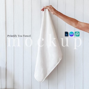 May include: White tea towel mockup hanging on a white wood panel background. The text "Printify Tea Towel Mockup" is printed on the background.