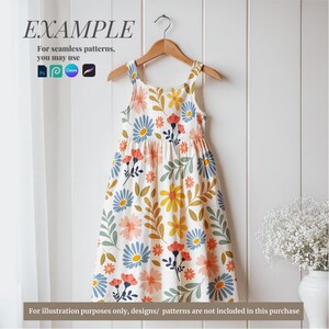 May include: A white sleeveless dress with a floral pattern featuring blue, yellow, pink, and green flowers. The dress has a gathered skirt and a fitted bodice. The dress is hanging on a wooden hanger against a white wood background.