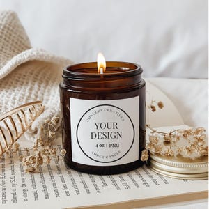 May include: A brown glass candle jar with a white label. The label has a black circle with the text "YOUR DESIGN" and "4 oz | PNG AMBER CANDLE" in white text. The candle is lit and the flame is visible.