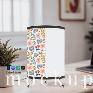 May include: A white tripod lamp with a floral pattern of blue, peach, and red flowers and green leaves. The lamp has a black top and base. The text "Tripod Lamp" is visible on the base.
