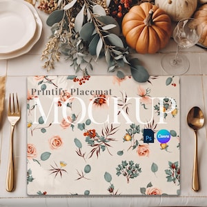 May include: A floral placemat mockup with the text "Printify Placemat MOCKUP" in a dining setting. The placemat features a cream background with pink roses, green leaves, and red berries. Gold cutlery, pumpkins, and plates are also visible.