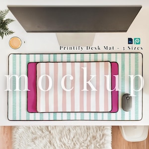 May include: A desk mat mockup with a striped design in shades of pink and white, with a teal border. The text "Printify Desk Mat - 3 Sizes" is visible. A smaller magenta desk mat is layered on top. A computer mouse is next to the desk mat.