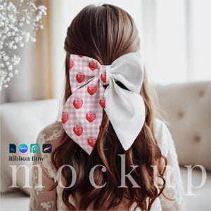 May include: A pink and white ribbon bow with a strawberry print. The bow is tied in a large knot and is worn in a girl's hair.