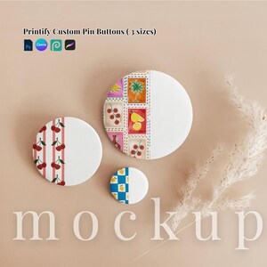 May include: Three circular pin buttons in varying sizes featuring diverse graphic designs. One button displays red cherries on pink stripes, another shows a grid of colorful food illustrations, and the smallest features a blue and white checkered pattern.