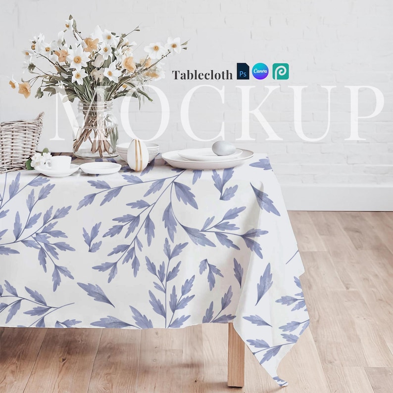 Może przedstawiać: Biały obrus z niebieskim wzorem kwiatowym, położony na drewnianym stole z wazą z kwiatami i ozdobnym jajkiem. Tekst "Tablecloth" jest widoczny w prawym g&oacute;rnym rogu obrazu.