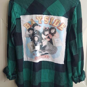 Puede incluir: Camisa de franela a cuadros verde y negro con un parche de Bayside Class of '93 en la espalda. El parche presenta un grupo de personas en una foto.