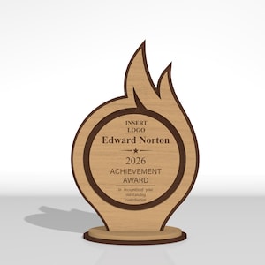May include: A light brown wooden award plaque shaped like a flame with a circular center. The text reads: INSERT LOGO, Edward Norton, 2026 ACHIEVEMENT AWARD, in recognition of your outstanding contribution. It features a dark brown border and base.