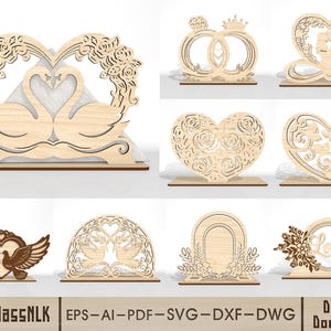 Puede incluir: Colección de elementos decorativos de madera cortados con láser, en color marrón claro, con diseños de cisnes, corazones y anillos. Presentan intrincados detalles florales y románticos. La palabra "Love" es visible en un elemento. Adecuado para bodas y eventos especiales.