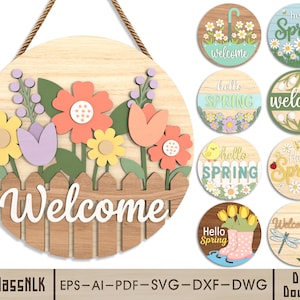 Op de afbeelding: Een houten welkomstbord met een bloemenontwerp. Het bord heeft kleurrijke bloemen, een houten hek en het woord "Welcome" in het wit. Extra ronde borden met "Hello Spring" en bloemenontwerpen worden ook getoond.