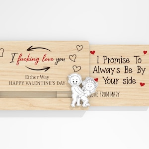 May include: A wooden Valentine's Day card with the text "I fucking love you" and "I promise to always be by your side." The card features a sliding mechanism and a cartoon couple illustration. Red hearts and the words "Happy Valentine's Day" are also present.
