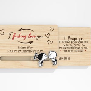 May include: A wooden Valentine's Day card with the text "I fucking love you" and "Happy Valentine's Day." The card features a sliding mechanism and a cartoon couple kissing. The second part of the card reads "I Promise..." and "From Mary."
