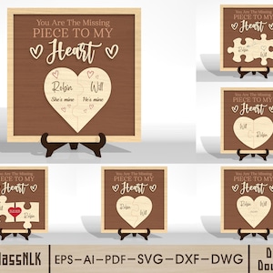 Puede incluir: Diseños de rompecabezas de madera en forma de corazón sobre un fondo marrón, enmarcados en madera clara. El texto dice "You Are The Missing Piece To My Heart" con nombres y frases. El diseño se muestra en un caballete de madera.