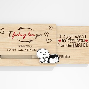 May include: A wooden Valentine's Day card with a sliding panel. The card features the text "I fucking love you" and "I just want to feel you from the inside." Decorative hearts and cartoon figures are also present.