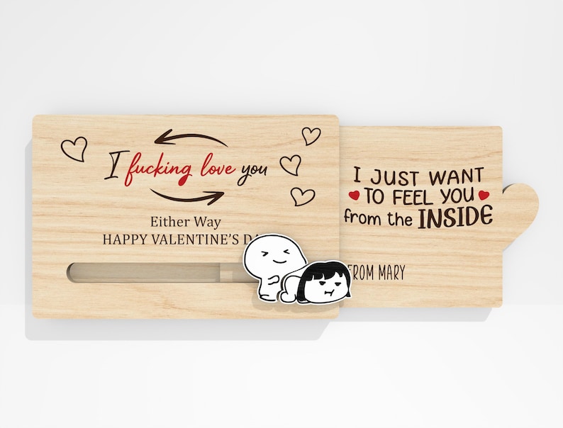 May include: A wooden Valentine's Day card with a sliding panel. The card features the text "I fucking love you" and "I just want to feel you from the inside." Decorative hearts and cartoon figures are also present.
