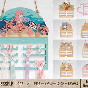 May include: A wooden mermaid-themed hair accessory organizer with a light blue base and a mermaid design. The organizer has slots for holding hair accessories, with various bows and ribbons displayed. The design includes coral and starfish accents.