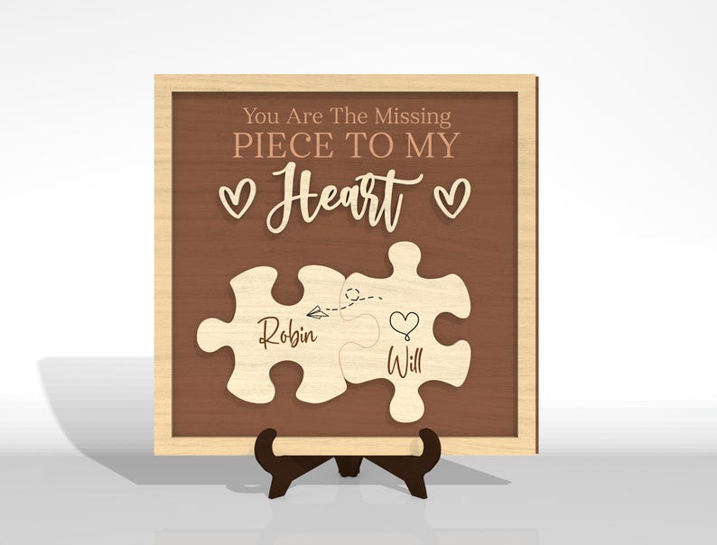 Puede incluir: Placa de madera con fondo marr&oacute;n y marco de madera clara. El texto "You Are The Missing Piece To My Heart" est&aacute; encima de dos piezas de rompecabezas. Las piezas del rompecabezas est&aacute;n etiquetadas como "Robin" y "Will".
