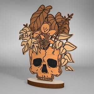 May include: A wooden skull planter with a brown base and a floral design. The skull is painted in a light orange color with black details. The planter is filled with a variety of leafy plants and flowers.