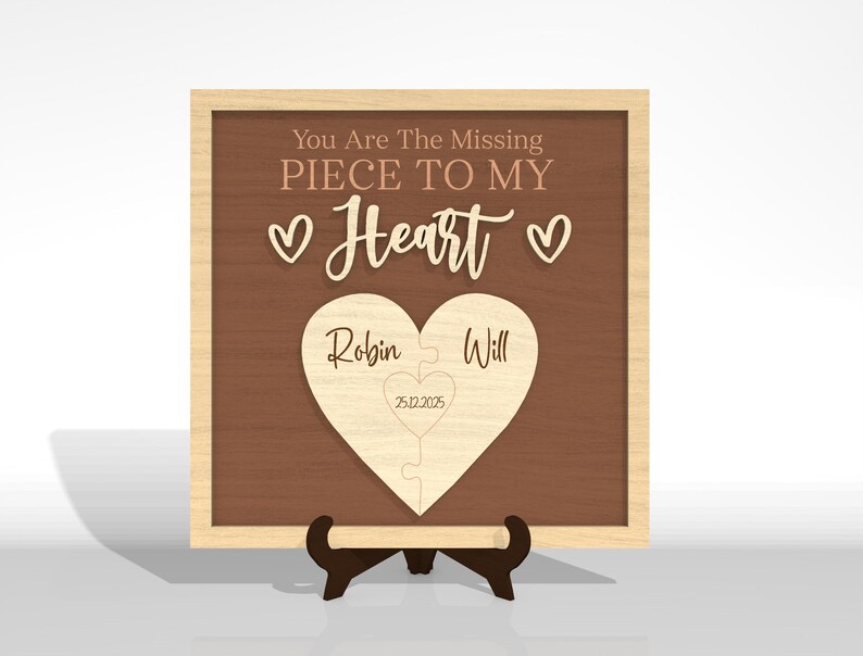 Puede incluir: Placa de madera con fondo marr&oacute;n y marco de madera clara. El texto "You Are The Missing Piece To My Heart" est&aacute; en la parte superior. Un rompecabezas en forma de coraz&oacute;n con los nombres "Robin" y "Will" est&aacute; en el centro. Tambi&eacute;n se incluye la fecha "25.12.2025".