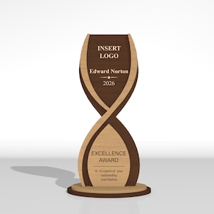 May include: A vertical wooden award trophy with a twisted hourglass shape, featuring dark and light wood tones. The top section displays the text INSERT LOGO, Edward Norton, and 2026. The bottom section features the text EXCELLENCE AWARD.