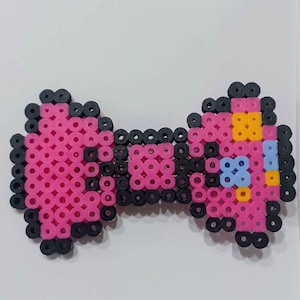 May include: A pink and black beaded bow tie with a blue and yellow center.