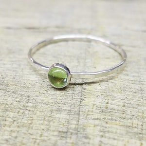 May include: A silver ring with a hammered finish and a green gemstone.
