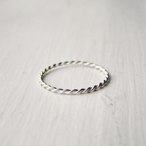 May include: A silver twisted band ring.