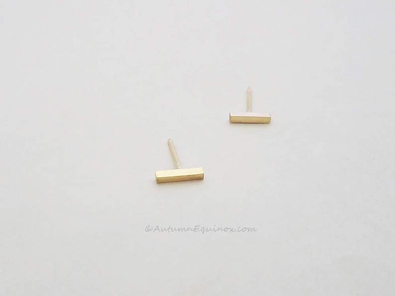 May include: A pair of gold bar stud earrings. The earrings are simple and minimalist, and they would make a great gift for a friend or loved one.