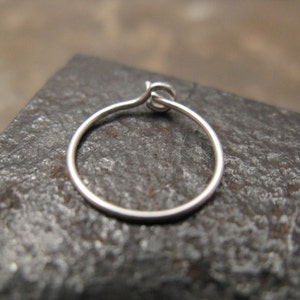 May include: A silver hoop earring with a simple, circular design. The earring is made of thin wire and has a smooth finish.
