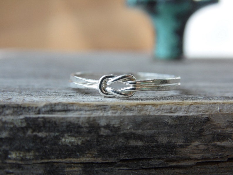 May include: A silver ring with a knot design. The ring is simple and elegant, and would make a great gift for a loved one.