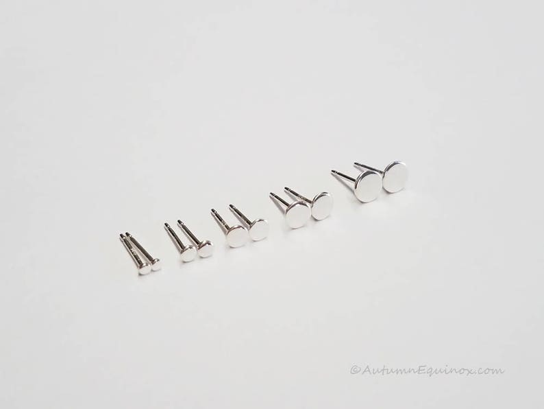 May include: A set of silver stud earrings in various sizes. The earrings are arranged in order of size, with the smallest on the left and the largest on the right.