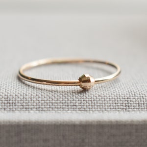 May include: A simple gold ring with a textured, faceted ball in the center.