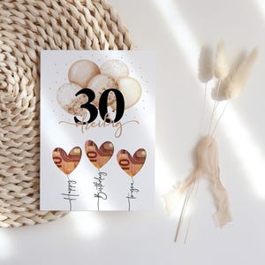 May include: A birthday card with the number 30 in black, the name "Shelby" in cursive, and three heart-shaped balloons with money inside. The balloons are labeled "Happy Birthday to you."