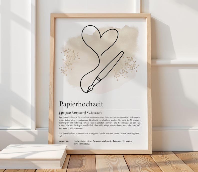 K&ouml;nnte beinhalten: Ein gerahmter Kunstdruck mit einem minimalistischen Design aus Herz und Stift, mit dem deutschen Wort "Papierhochzeit" unten. Das Kunstwerk hat eine neutrale Farbpalette mit beige und schwarzen Elementen, passend f&uuml;r die Inneneinrichtung.