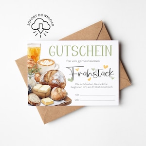 Könnte beinhalten: Ein druckbarer Frühstücksgutschein mit Aquarellillustrationen von Kaffee, Brot und Gebäck. Der deutsche Text lautet "GUTSCHEIN Frühstück" mit Platz zum Schreiben von "FÜR" und "VON". Ein brauner Umschlag befindet sich dahinter.