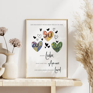 May include: A white card with black text and hearts. The text reads "Zur Hochzeit w&uuml;nschen wir euch von Alles Liebe, Amore Love!" with euro bills folded into heart shapes around the text.