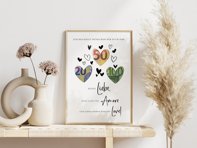 May include: A white card with black text and hearts. The text reads "Zur Hochzeit w&uuml;nschen wir euch von Alles Liebe, Amore Love!" with euro bills folded into heart shapes around the text.
