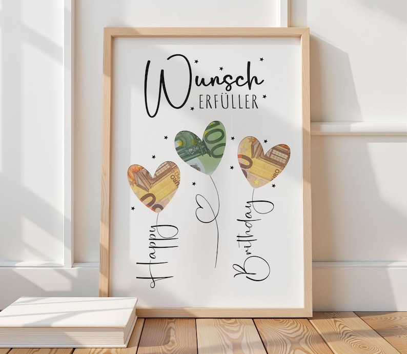 May include: A framed print with the words "Wunsch Erf&uuml;ller" and "Happy Birthday" in script. Three heart-shaped balloons are filled with Euro banknotes. The frame is light brown, and the background is white.